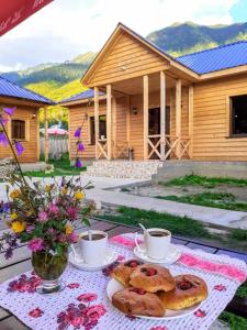 una mesa con dos tazas de café y algunos pasteles en Guest House Ushba Gate, en Mestia