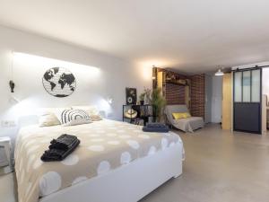 a white bedroom with a large bed and a chair at CHEZ ADELA in Almoster