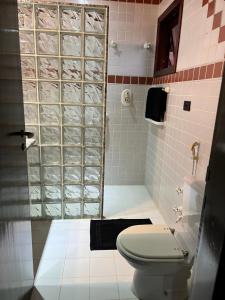 a bathroom with a toilet and a glass shower at Vila husky pousada in Campos do Jordão