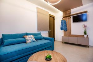 a living room with a blue couch and a table at Vela Bianca Suites in Limenaria