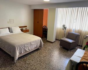 Habitación de hotel con cama y silla en Hotel Plazza, en Chiclayo