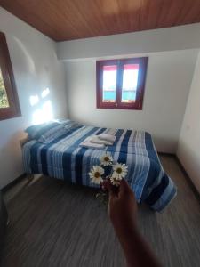 una persona sosteniendo flores frente a una cama en Kapaq Country House, en Cusco