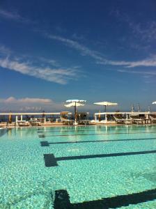 a swimming pool with blue water and chairs and umbrellas at La Rosa dei Venti Resort in Piombino