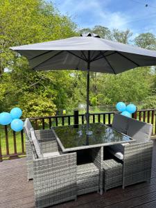 a table and chairs under an umbrella on a deck at Lakeview Lodge, Builth Wells (pet friendly) in Builth Wells