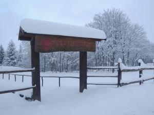 una señal cubierta de nieve con árboles en el fondo en Normena Mountain Residence, en Tizzano Val Parma