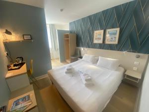 a bedroom with a large white bed with a blue wall at H&ocirc;tel De Wimereux in Wimereux