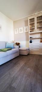 a living room with a white couch and wooden floors at SunDays House #casa al mare in Quartu SantʼElena