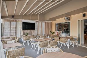 un restaurante con mesas y sillas y TV de pantalla plana en Acropolis Apartments, en Hersonissos