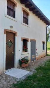 Fara Vicentino的住宿－La Colombara，院子中一扇门和鲜花的白色房子