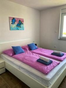 a large bed with pink sheets and blue pillows at Apartman Anavi in Sveti Vid-Miholjice +13 photos