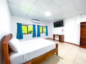 sypialnia z łóżkiem z niebieskimi zasłonami i telewizorem w obiekcie Majahual Resort w mieście El Majahual