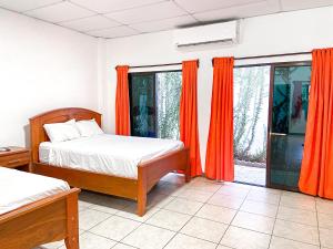 sypialnia z 2 łóżkami i pomarańczowymi zasłonami w obiekcie Majahual Resort w mieście El Majahual