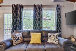 a brown leather couch in a living room with windows at Chic and Stylish home Hot tub,4 bedrooms, game movie room, firepit, arcades, playground on site 2 min walk from pool and lake in Tobyhanna