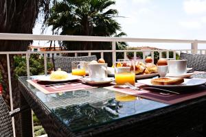 a table with breakfast food and orange juice on a balcony at Mi Casa és Su Casa in Prainha