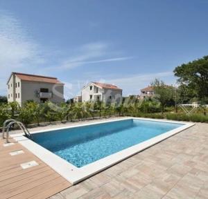 a swimming pool in front of a house at Apartman Anavi in Sveti Vid-Miholjice