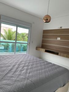 a bedroom with a large bed and a window at Casa em Guarujá-Jardim Acapulco in Guarujá