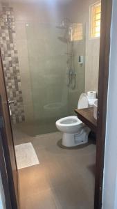 a bathroom with a toilet and a glass shower at Paramount 3-Bedroom Apartment with Parking in San Felipe de Puerto Plata