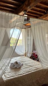 a bedroom with a bed with white sheets and curtains at Agriturismo Casallario in Volterra