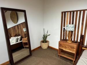 a mirror in a bedroom with a bed and a table at Njombe Cozy House in Njombe