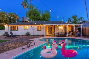 a swimming pool with three pink flamingos in it at Sunshine Oasis! Heated Pool, Mini Golf, Sleeps 12 in Scottsdale