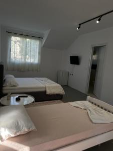 a bedroom with two beds and a window and a table at Sunny Rentals in Vlorë