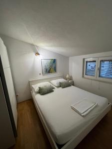 białe łóżko w pokoju z 2 oknami w obiekcie Apartments Kapetanovi Dvori w Trogirze