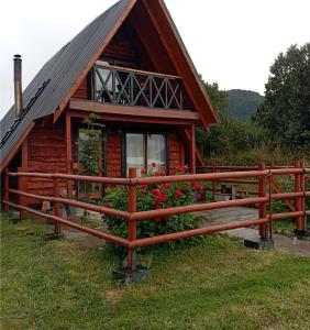 uma cabana de madeira com uma cerca em frente em CABAÑA PARCELA VISTA HERMOSA em Puerto Aisén