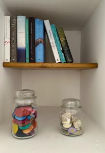 two glass jars sitting on a shelf with books at Casa Thamay in Brindisi