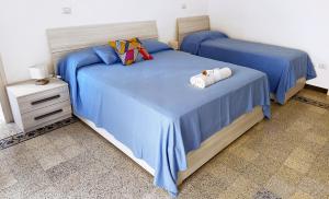 two beds in a bedroom with blue sheets and pillows at Casa Thamay in Brindisi