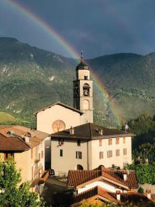 a rainbow over a building with a clock tower at L'angolo del buonumore in Daone