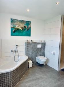 a bathroom with a bath tub and a toilet at Ferienwohnung Gold-Blick in Korbach