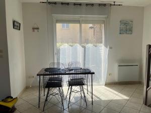 a dining room table with three chairs in front of a window at Maison T3 avec petit jardin in Valras-Plage