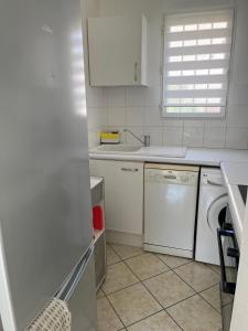 a white kitchen with a washing machine and a window at Maison T3 avec petit jardin in Valras-Plage +8 photos