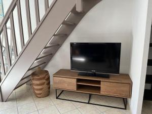 a tv sitting on a wooden cabinet under a staircase at Maison T3 avec petit jardin in Valras-Plage