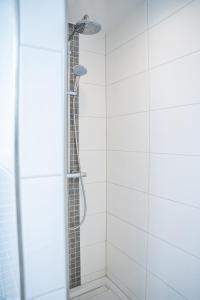 a shower in a bathroom with white tiles at Ferienwohnung Gold-Blick in Korbach