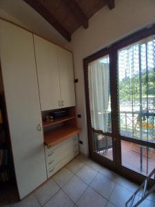 a kitchen with white cabinets and a sliding glass door at Villetta Tora in Santo Stefano di Magra