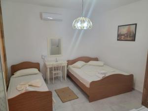 2 Betten in einem Zimmer mit einem Tisch und einem Spiegel in der Unterkunft Vila Islami in Durrës