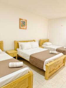 um quarto com três camas num quarto em Hotel Ginebra Sincelejo em Sincelejo