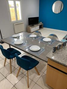a table with chairs and plates on it in a kitchen at Maison des romains in Villeneuve-sur-Lot