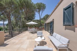 a patio with a couch and tables and chairs at Casa La Vinya con parking y piscina - WeHost Costa Brava in Palafrugell