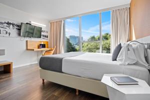 um quarto de hotel com uma cama grande e uma janela grande em Own Montevideo em Montevidéu