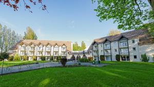 a large building with a green lawn in front of it at Hippotel in Le Touquet-Paris-Plage