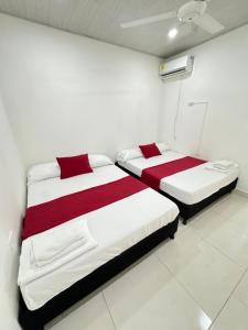TORRES DEL MESÓN LUXURY APARTA HOTEL Doradal في Doradal: سريرين في غرفة ذات أغطية حمراء وبيضاء