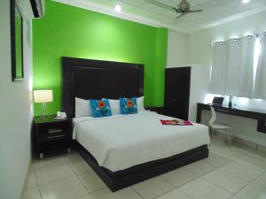 a bedroom with a bed and a green wall at Chiapas Hotel Express in Tuxtla Gutiérrez