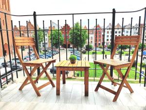dwa drewniane krzesła i stół na balkonie w obiekcie Apartament Ania Stare Miasto w Elblągu
