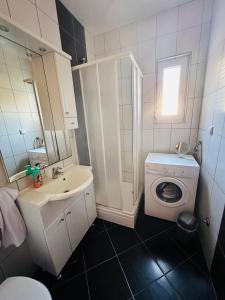 uma casa de banho com um lavatório e uma máquina de lavar roupa em Appartement für 7: Zentrale Lage mit Privatparkplatz em Novalja