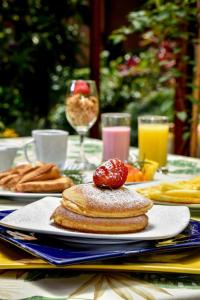 a table with a plate of pancakes with a strawberry on top at La Campana Hotel Boutique in Medellín