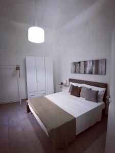 a bedroom with a large white bed and a light at Tra mare e profumi in Trapani