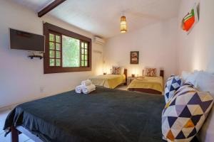 a room with two beds and a flat screen tv at Pousada Casa Cactus Praia da Tartaruga Búzios in Búzios