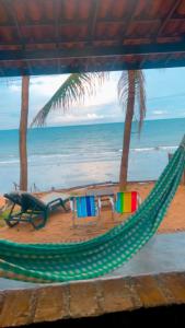 a hammock on a beach with a view of the ocean at Suíte pé na areia in Icapuí